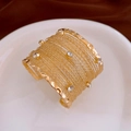 Detailed shot of a wide multi-layer gold alloy cuff bracelet featuring white rhinestones - Gold