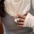 Close-up of a large silver 3D heart pendant on a round bead chain necklace worn by a model - Large Polished Silver Heart Style (1)