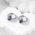 Detail view of silver hoop earrings with natural blue marble stones on white stone base - Dark Blue Natural Stone