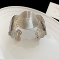 Makroaufnahme der silbernen geometrischen Armspange mit Spiraltextur und breitem C-Design - Groß (Umweltfreundlich) / Silber