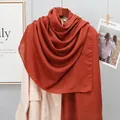 Detailed close-up of a caramel linen cotton scarf texture on a wooden hanger - Caramel