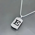 Macro shot of silver hollow letter pendant and durable titanium steel box chain - Letter E