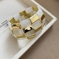 Detail eines quadratischen Acryl-Marmor- und goldenen Metall-Manschettenarmbands - Weiß