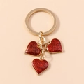 Golden keychain featuring three red sparkling heart charms with shimmering glitter finish - Large Heart / Red