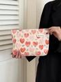Close-up of model holding a beige heart-patterned fabric makeup bag with woven label - Large Contrast Pink Heart