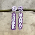 Lilafarbene Glitzer-Acrylohrringe mit Cheer-Mama-Schriftzug an einem Dekozweig hängend - Lila