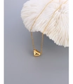 Detail of polished gold heart pendant hanging on a white coral stone display - Heart Gold