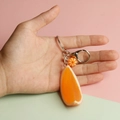 Detail of realistic orange slice keychain with flower charm and silver clasp in hand - Orange Wedge