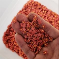 Close-up of mini red resin nail art flowers with yellow centers held in hand - Hawthorn Red