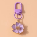 Detail of purple flower keychain with gold edging and matching metal ring on orange base - Purple