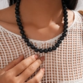 Detail shot of vintage acrylic beaded necklace featuring glossy black round beads on a model - Necklace / Black