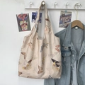 Nahaufnahme einer cremefarbenen Canvas-Tasche mit Schmetterlingsdruck an einem Wandhaken - Aprikosen-Schmetterling