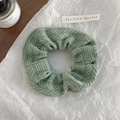 Macro shot of light green knitted hair scrunchie with soft ribbed texture and wavy edges - Green