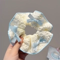 Détail d'un chouchou beige avec nœuds en satin bleu clair et tissu plissé texturé - Chouchou Nœud Bleu