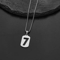 Detail of silver stainless steel number 7 pendant on box chain over grey stone - Number 7