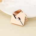 Macro detail of rose gold envelope locket pendant with an inner insert card on a plate - Envelope Set / Rose Gold