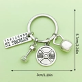Silver fitness keychain with dumbbell and kettlebell charms on a light green background - LS183-STRONG IS BEAUTIFUL