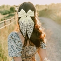 Rear view of a model wearing a large cream lace bow hair clip with long flowing ribbons - White