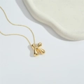 Macro shot of 3D gold letter K pendant on a fine chain over a textured tray - Letter K