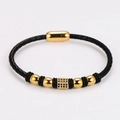 Detalle de pulsera de cuero trenzado negro con cierre magnético dorado y piedras - Dorado