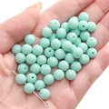 Mint green matte acrylic round beads for DIY jewelry making held in a hand closeup - Aqua Green