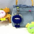Close-up of blue fuzzy monster plush keychain with googly eyes hanging on denim bag - Royal Blue