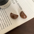 Minimalistische kaffeebraune Harz-Ohrstecker in C-Form auf einem offenen Vintage-Buch - Dunkelbraun