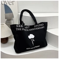 Borsa tote minimalista in tela nera con stampa floreale e scritta NKK ART STUDIO - Nero