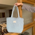 Detailansicht der hellblauen Bubble-Textur und des gewebten Logo-Etiketts an der Schultertasche - Blasen-Blau