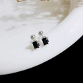 Macro shot of titanium steel screw-back stud with rectangular black zircon and side accents - Square Bow / Steel