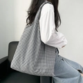 Side view of a large black and white checkered canvas tote bag worn by a model - Black Plaid