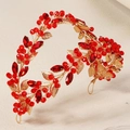 Detail of a gold bridal headband with sparkling red rhinestones and metallic leaf design - Gold Red Crystal