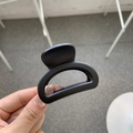 Detail shot of a small matte black butterfly hair claw clip held in hand for hair styling - Matte Black