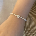 Detail of beaded alphabet bracelet with gold G pendant on a female wrist - Letter G Style (G)