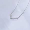 Macro detail of V-shaped silver pendant set with sparkling cubic zirconia on textured fabric - 925 Silver / Silver