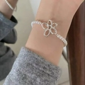Elegant pearl bracelet featuring a silver hollow flower charm on a wrist model - Silver Hollow Flower Pearl (MY37401)