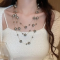 Detail showing elegant triple-layer gold chain necklace with grey pearls on a model - Gold Grey