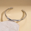 Dettaglio del bracciale rigido ondulato argento posizionato su supporto in pietra - Argento