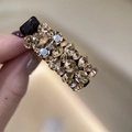 Gros plan d'une pince à cheveux noire avec des strass champagne étincelants en main - Champagne