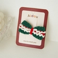 Macro shot of green and red handmade knitted bow hair clip on branded card display - Christmas Bow