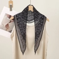 Detailed macro shot of a black paisley bandana hanging on a wooden hanger with a beige top - Black