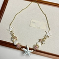Macro shot of gold necklace with white starfish, seashells and pink crystal floral accents - White Starfish Necklace I-22