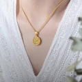 Collana vintage dorata con ciondolo tondo a rilievo floreale indossata da una modella - 41+5cm / Oro