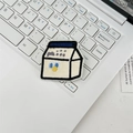 Close-up of a cartoon milk carton embroidery patch on a laptop keyboard background - Milk Box