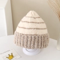 Close-up of cozy striped knitted beanie for kids on a minimalist display stand - 2-5 Years Old / Off White
