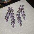 Detailed close-up of silver flower earrings featuring purple crystal petals and leaf design - Purple
