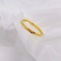 Macro detail of gold-tone geometric faceted bangle on white satin background - Gold