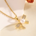 Detail of gold bow necklace with white pearl and micro-set crystals on fabric - Gold Pearl Bowknot Necklace
