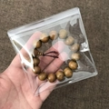 Transparent PVC jewelry storage bag holding a natural light brown wooden bead bracelet - 100 Pieces / 11*11cm (26 Microns)