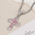 Detailed macro view of a silver cross pendant featuring pink and white zircon gemstones - Cross / Silver Chain with Pink Pendant
